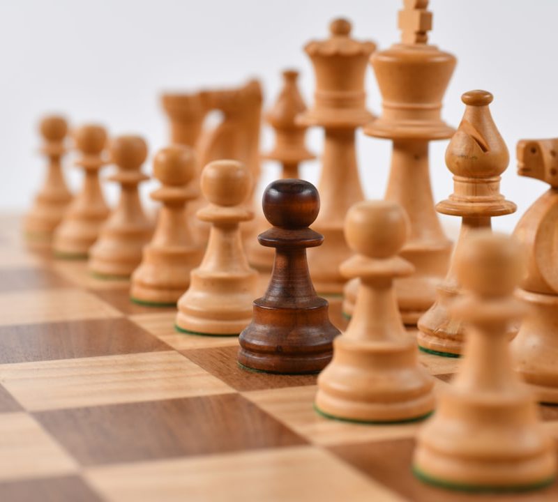 Wooden chess set with ivory and ebony pieces on a walnut board, photographed in warm studio light.